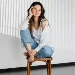 Une femme chez elle assise sur un tabouret